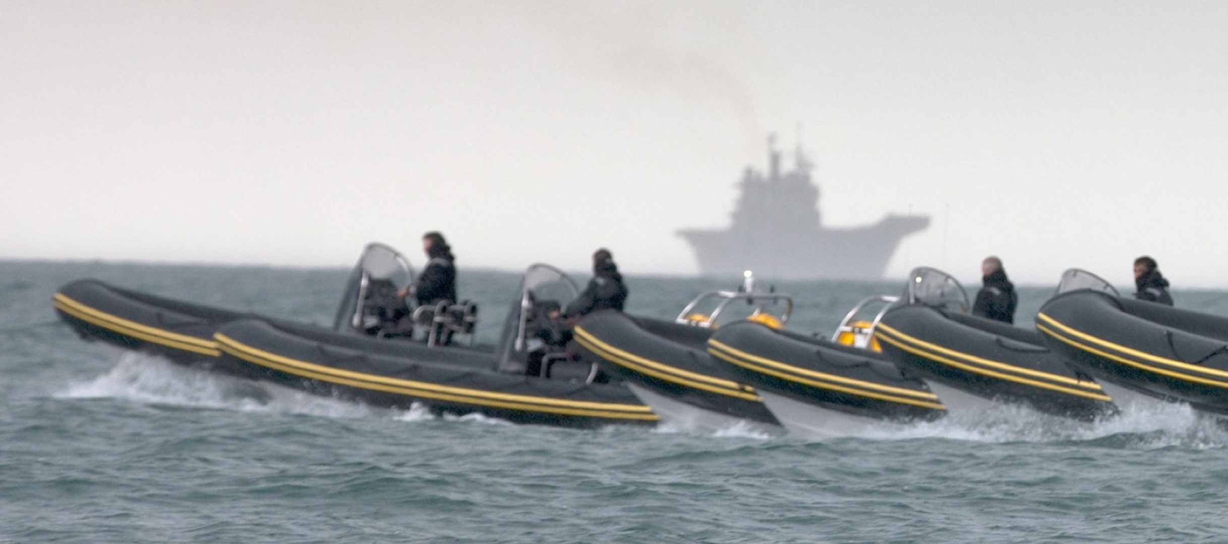Solent Rib Charter fleet of high-performance RIBs travelling at speed across open water with a naval vessel visible on the horizon.