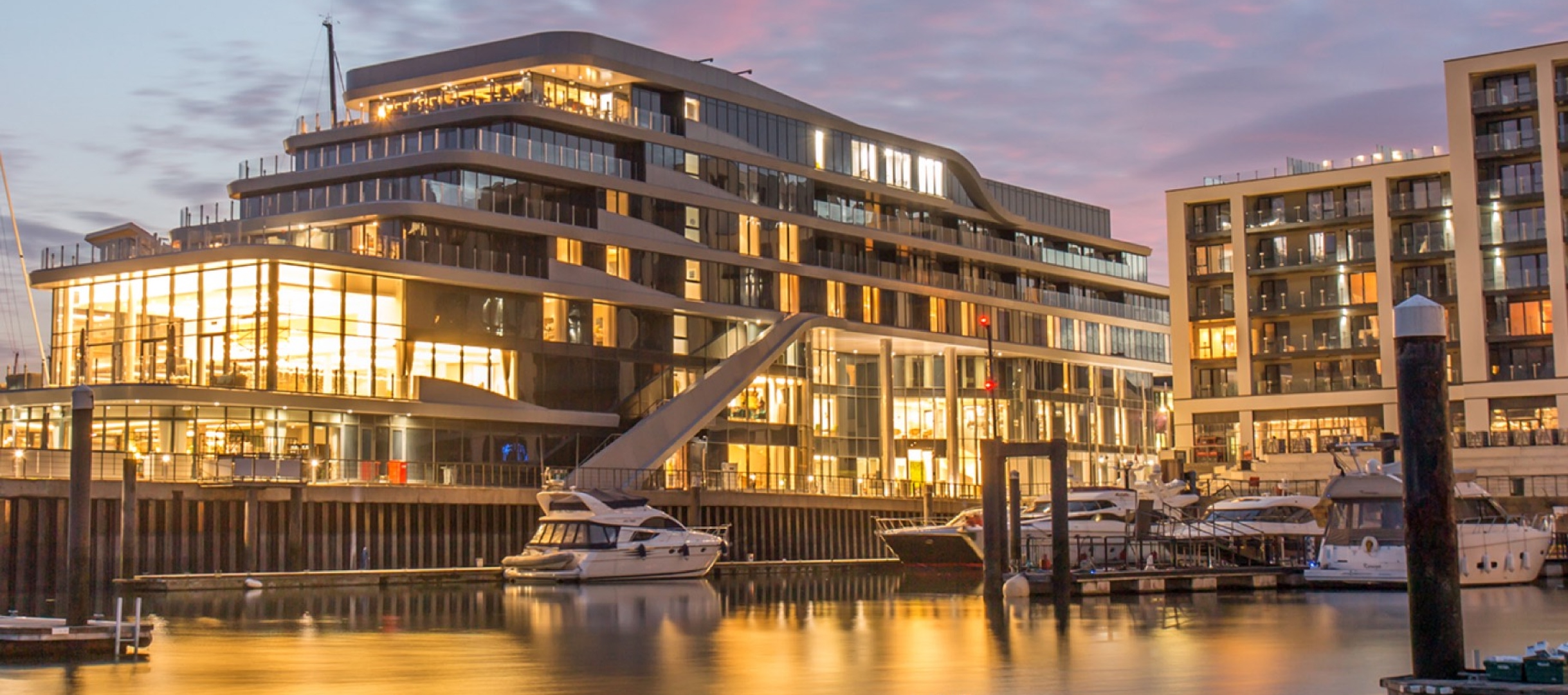 Ocean Village Marina in Southampton at sunset with luxury yachts moored beside the illuminated Harbour Hotel