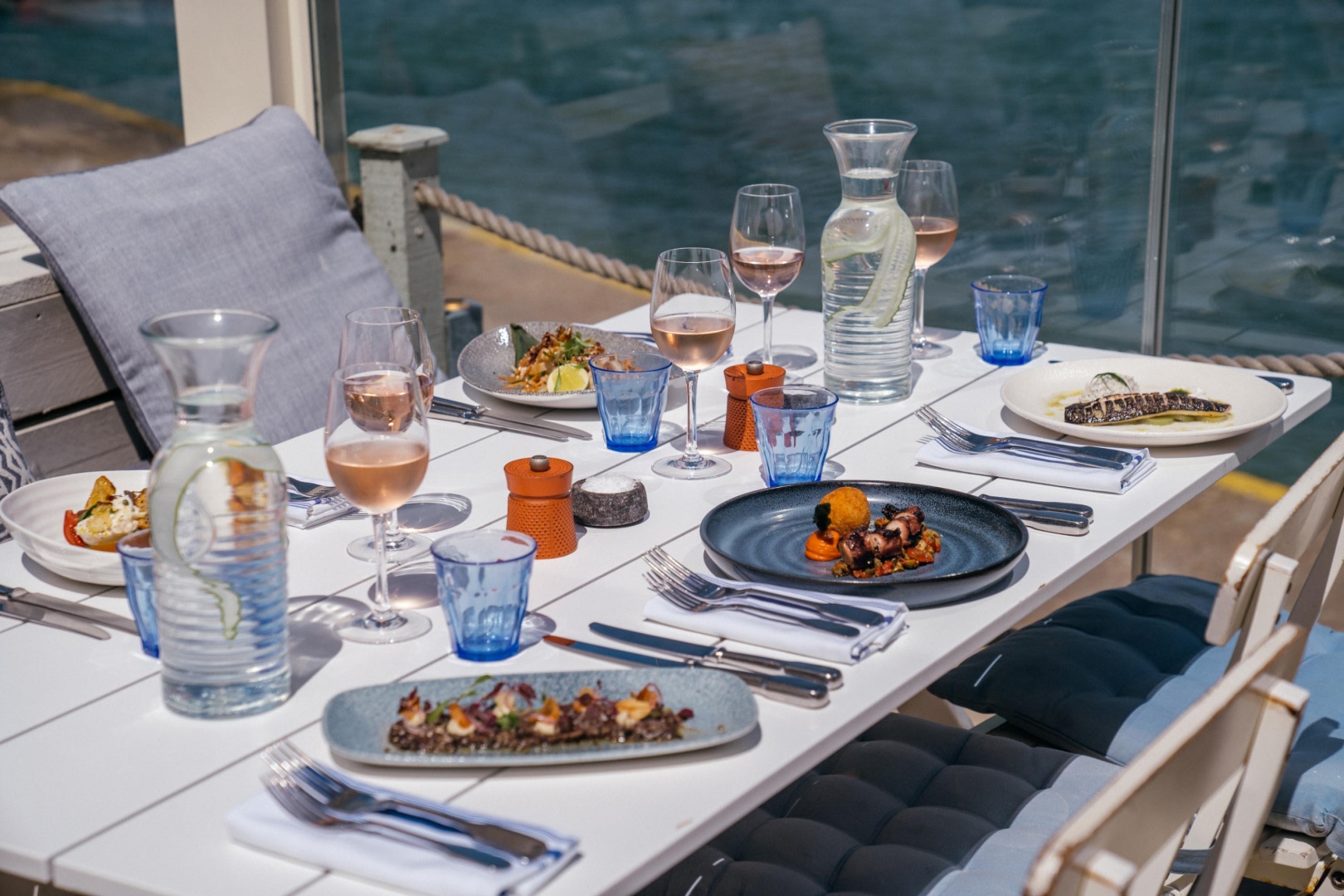 Luxury outdoor dining table at The Hut Restaurant with seafood dishes, rosé wine and ocean views, highlighting premium shore experiences offered by Solent Rib Charter.