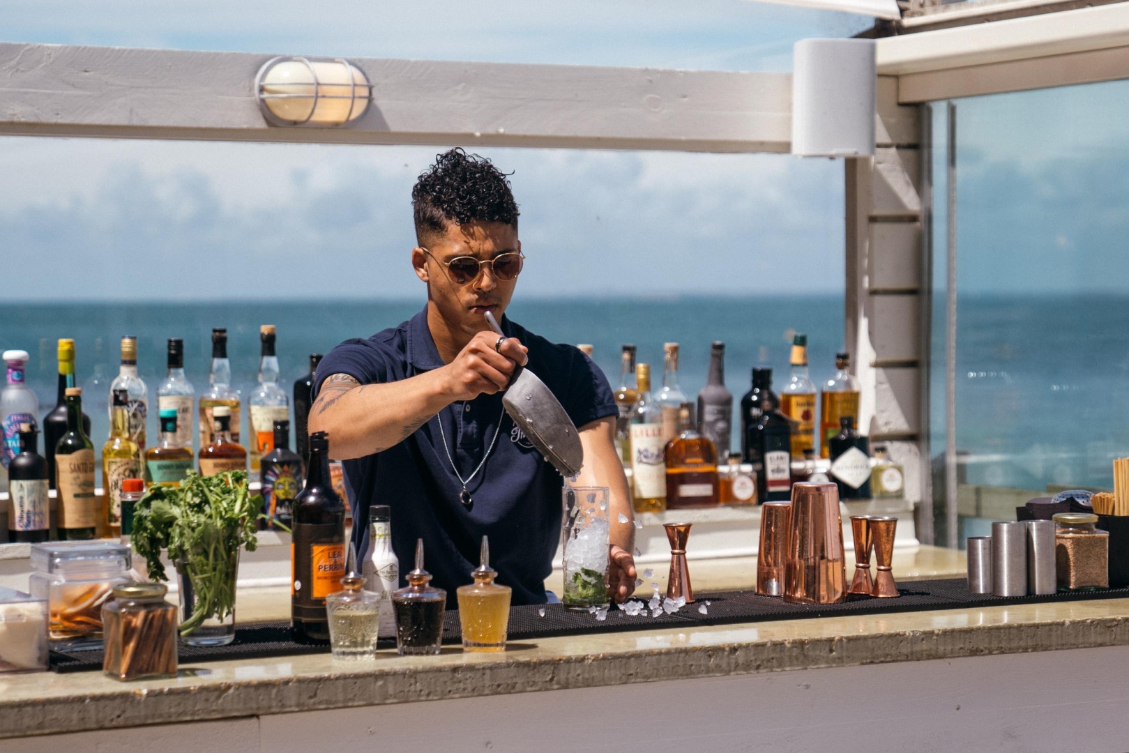 Bartender preparing cocktails at a beachfront bar with ocean views, ideal for Solent Rib Charter post-charter hospitality experiences