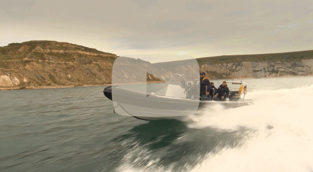 Solent Rib Charter boat speeding along rugged coastal cliffs, giving passengers an exhilarating on-water adventure and scenic views.