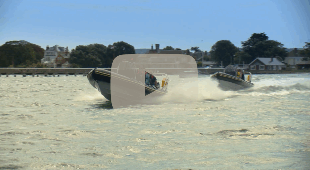 Two Solent Rib Charter boats speeding across choppy coastal waters near the shoreline, showcasing high-performance RIB handling and exciting on-water experiences.