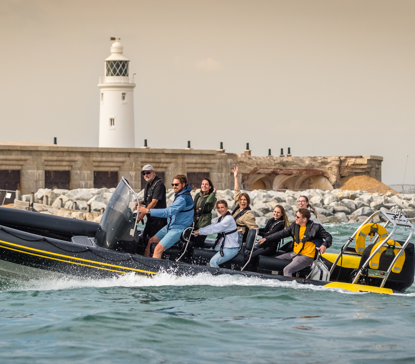 Group enjoying high-speed Solent Rib Charter experience passing coastal lighthouse on a guided RIB boat adventure