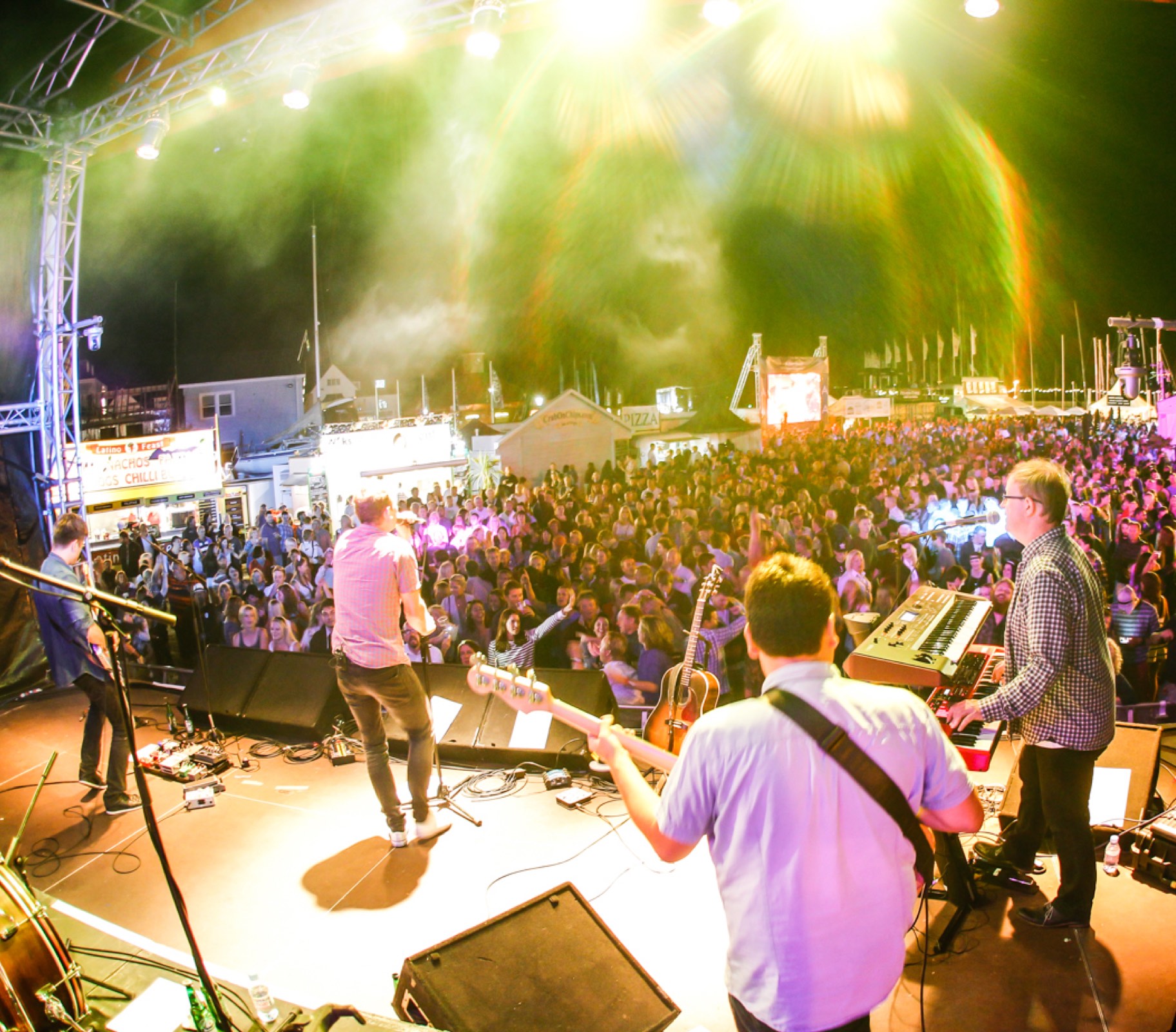 Live band performing on stage to a large outdoor crowd at night