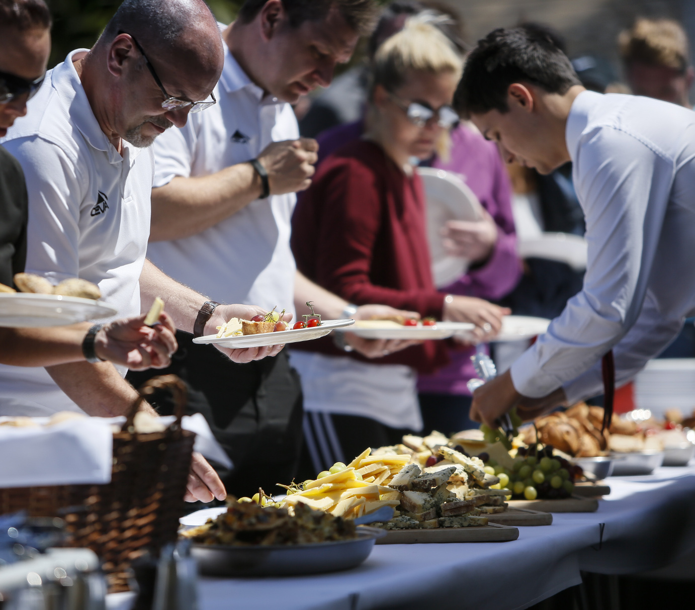 People serving themselves food at an outdoor buffet during a group event